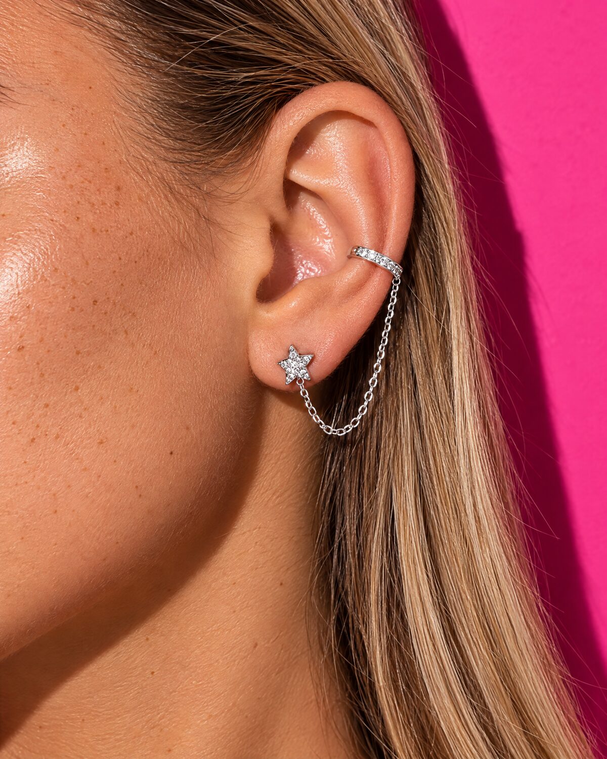 Ear cuff con catenina e orecchino a stella su fondo rosa